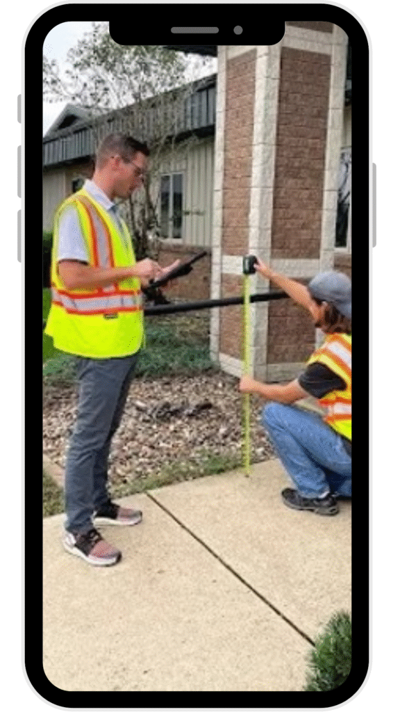 Two workers surveying sidewalk with measuring rod