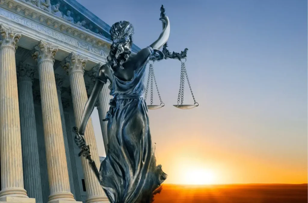 Lady Justice statue with courthouse columns at sunrise