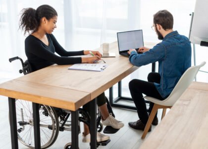 Woman in wheelchair meeting colleague at desk