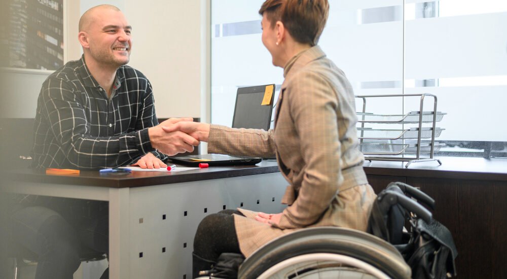 Man and woman shaking hands, woman in wheelchair
